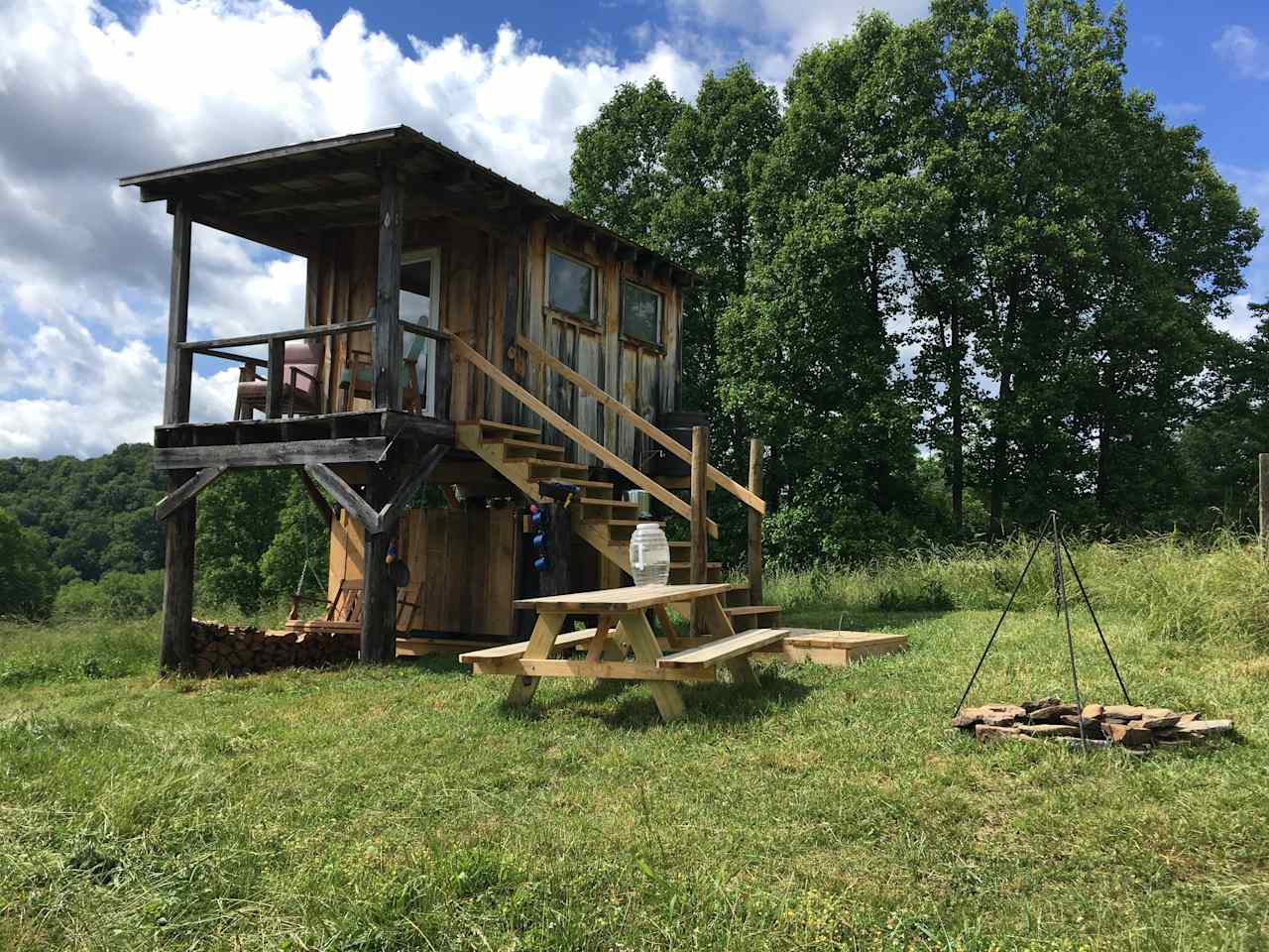 The Reformed Hunting Cabin features a firepit with hanging cookpot, cookware in the cabin, compostable toilet, and swing. 