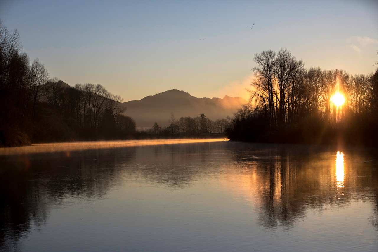 The sun rises over the Skagit River and the camping spot on the right.