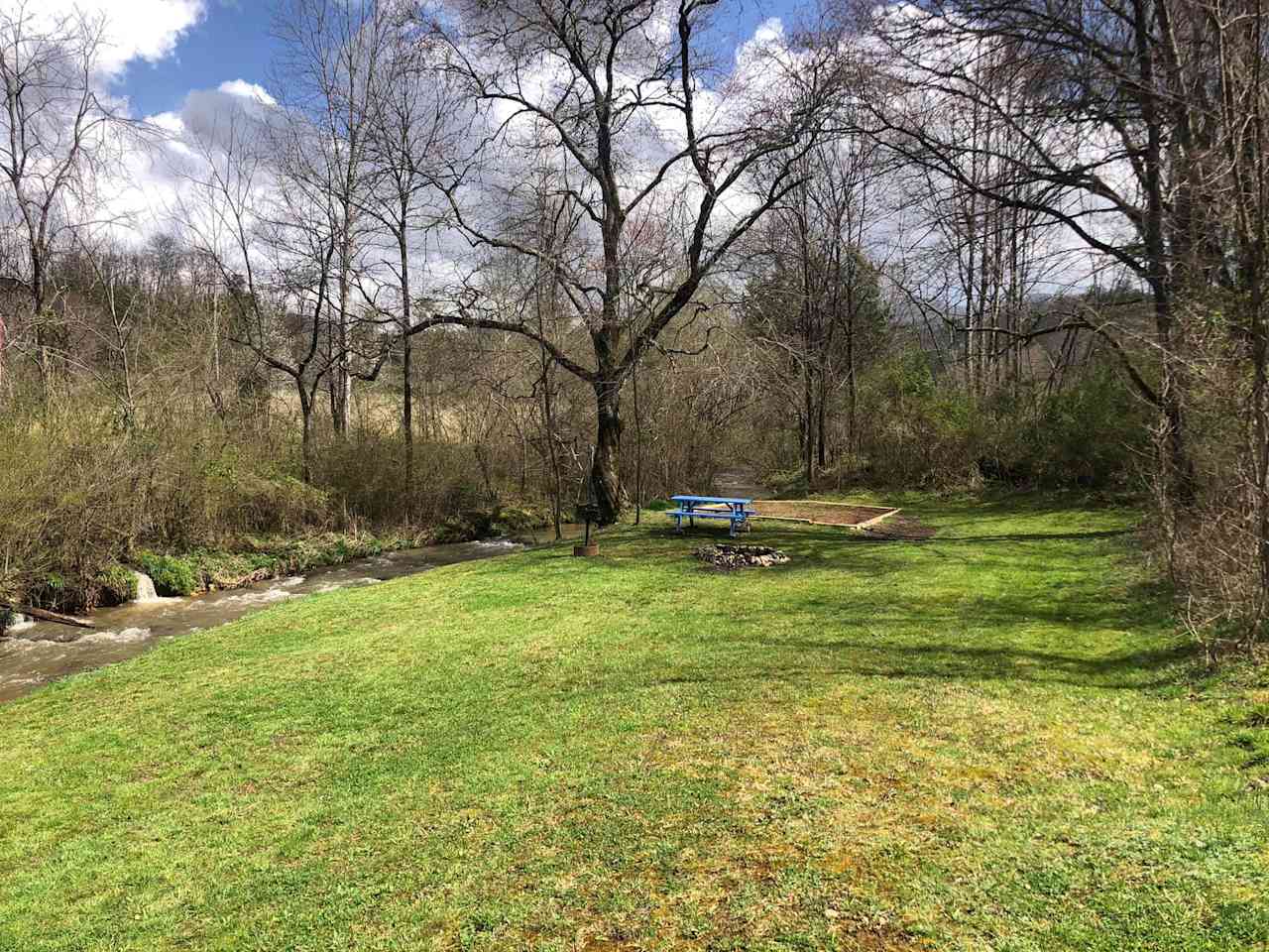 Site #1 Creekside has a 16' tent pad, picnic table, rock fire pit and a park style charcoal grill. 