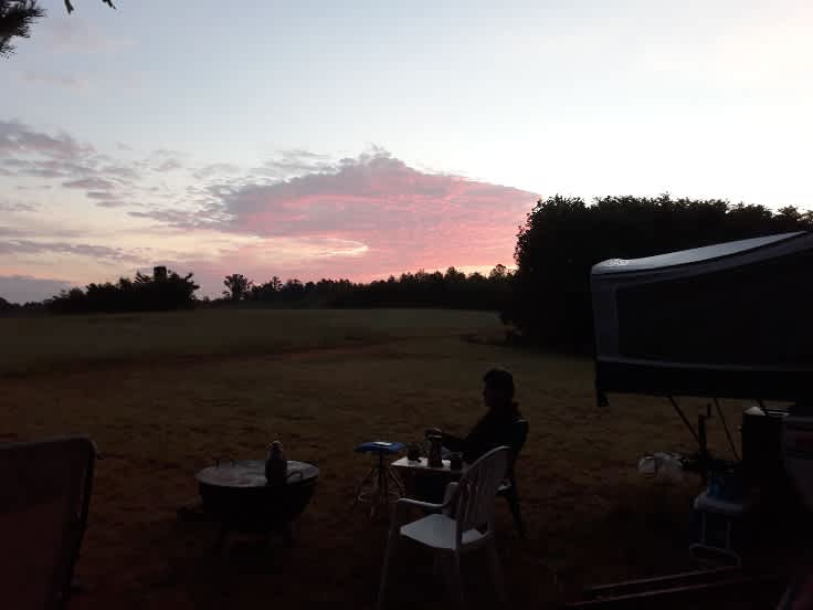 Having coffee in the middle field at sunrise