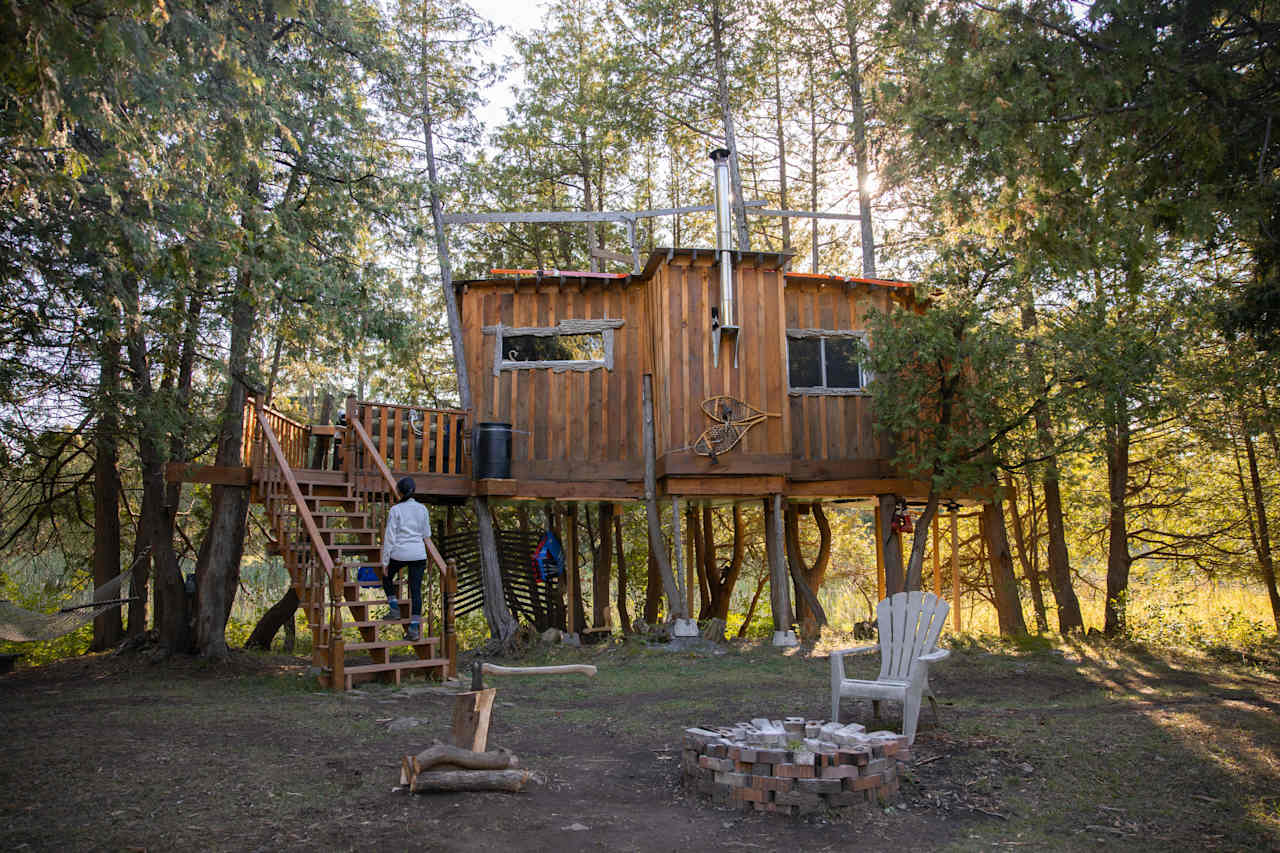 A guest climbing the wooden staircase that leads to the upper patio and the treehouse entrance. 
