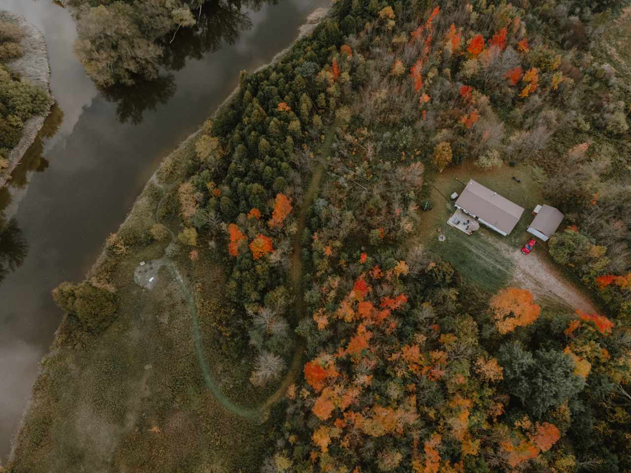 An overview of the cottage, trail, and camp area by the river