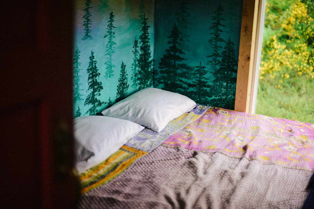 Queen bed inside the cabin. There is a quilt and extra blankets.