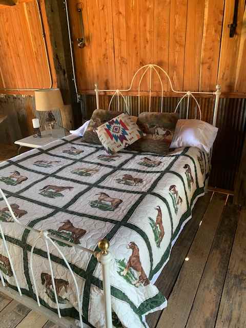 Cozy double bed made with crisp white linens on a vintage iron bed frame. 