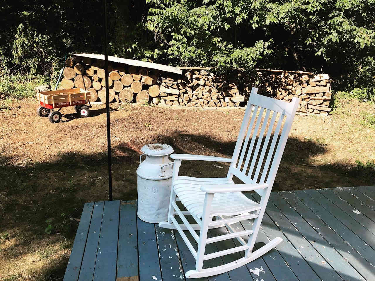 Plenty of pre-split stacked wood and a Radio Flyer for gathering kindling around the property. Use the vintage milk jugs as a side table.