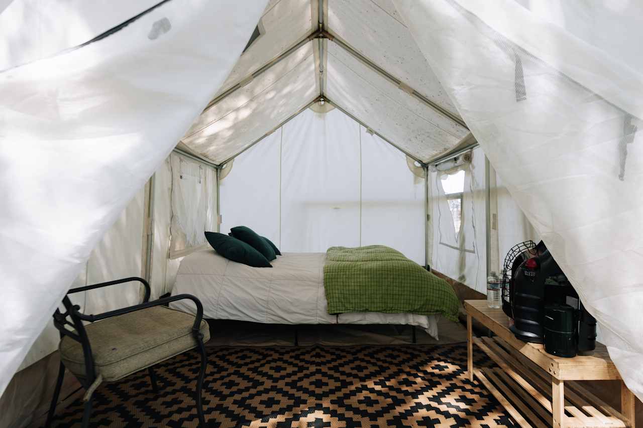 The glamping tent is outfitted with a comfy memory foam bed, chair, and propane heater