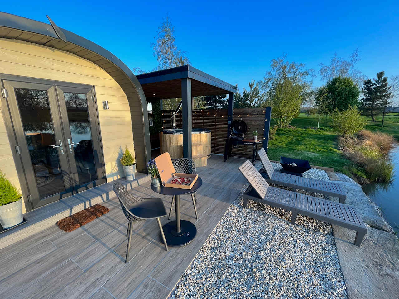 Your spectacular outdoor area consists of wood-fired hot tub, fire pit, BBQ, sun-loungers, table & chairs, fish from your your pod, lakeside & beautiful sunset views, pizzas can also be delivered to the site. 