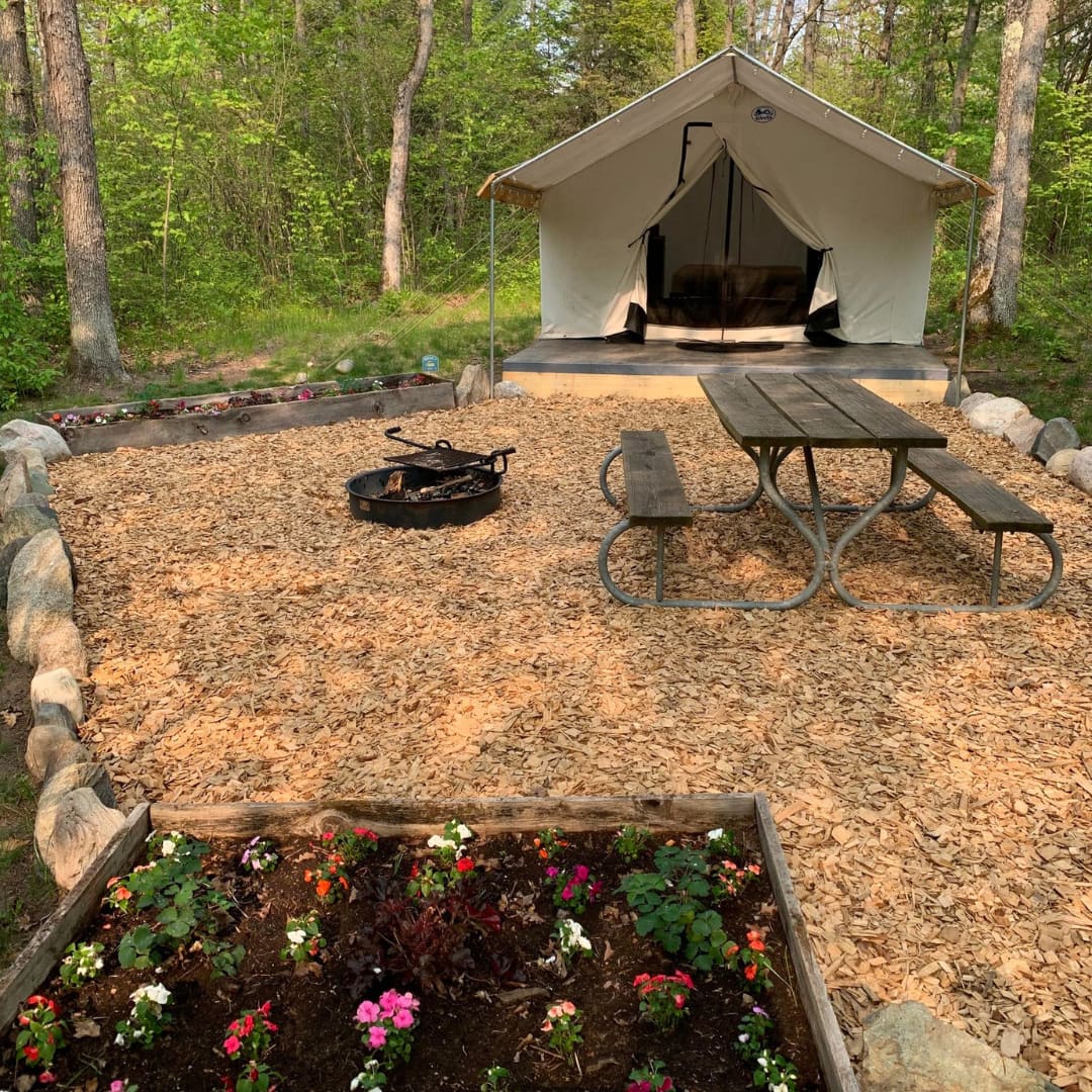 Fire pit with adjustable grate for cooking, picnic table, locking trash can, and flowers to admire!