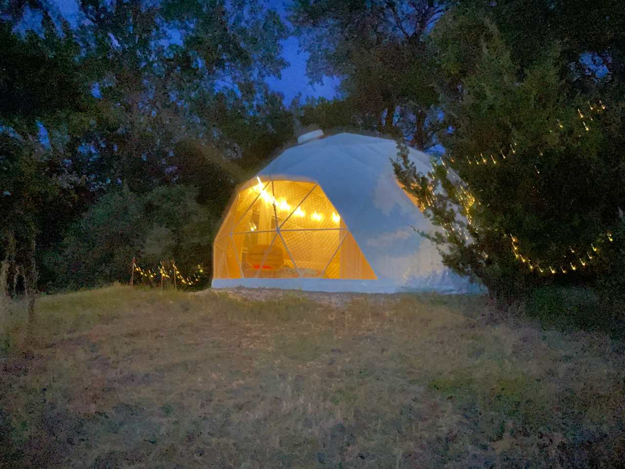 The Fantastic Geodesic tent during night with the lights on powered by a aolar battery.