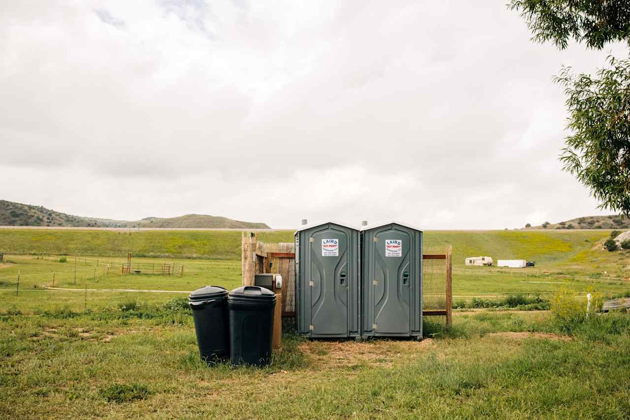 Bathrooms and trash located under the tree next to the sites. 