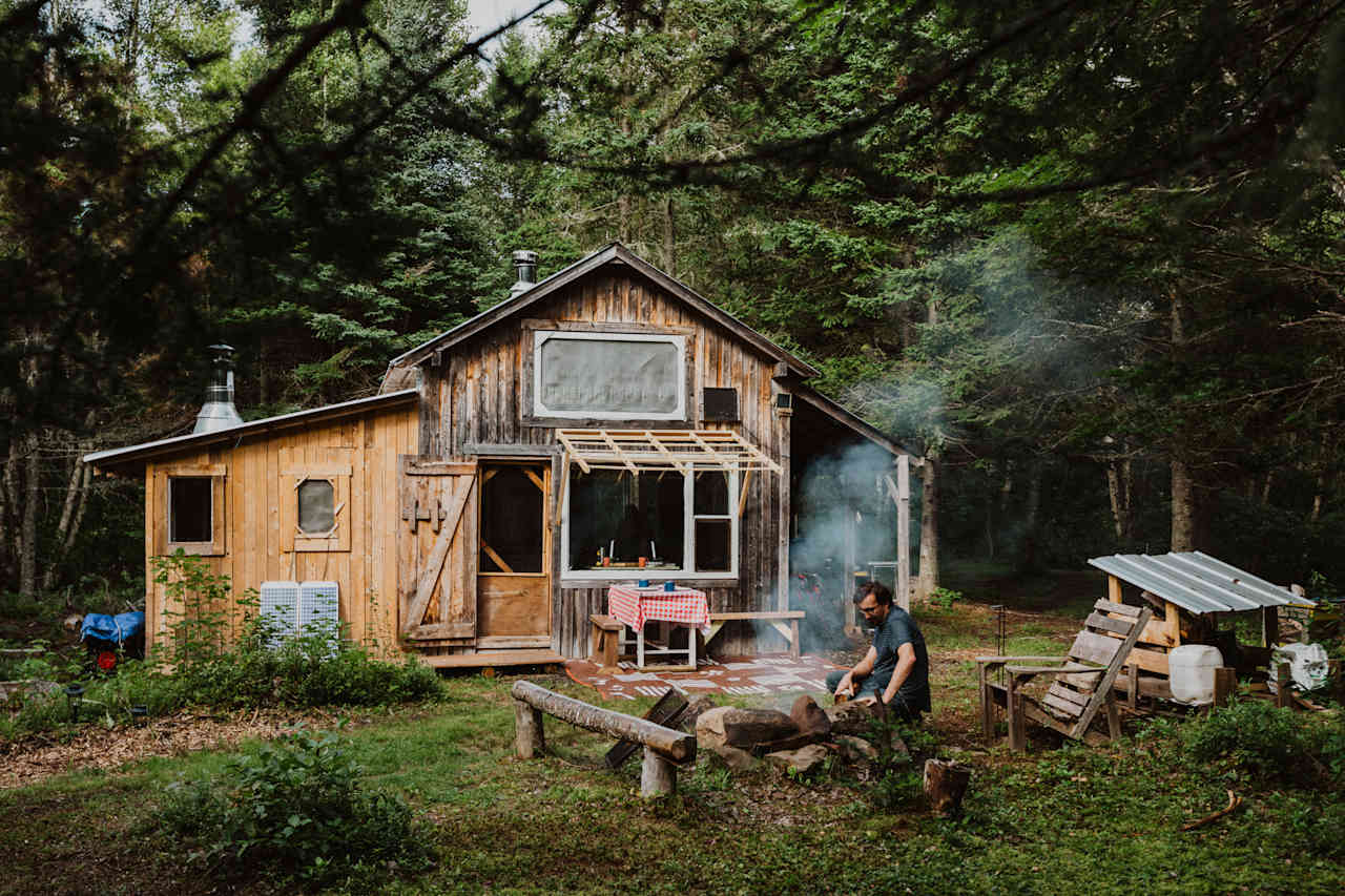 View of the cabin and the fire pit, including extra wood