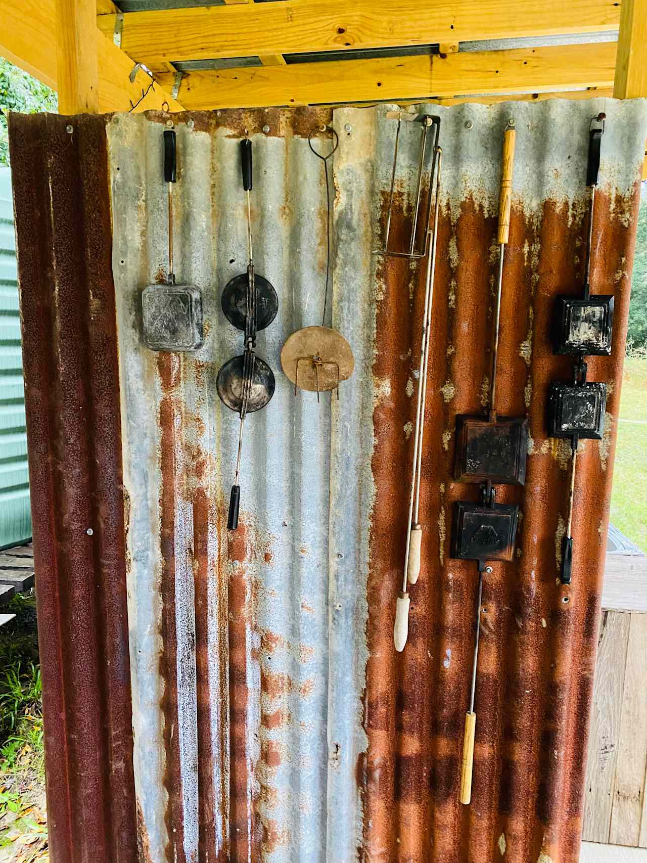 Closeup of jaffle irons/toasting fork hanging under covered camping shelter. 