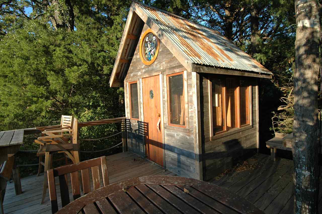 The handcrafted  Hummingbird Treehouse made with reclaimed cedar fence pickets and rusted tin roofing