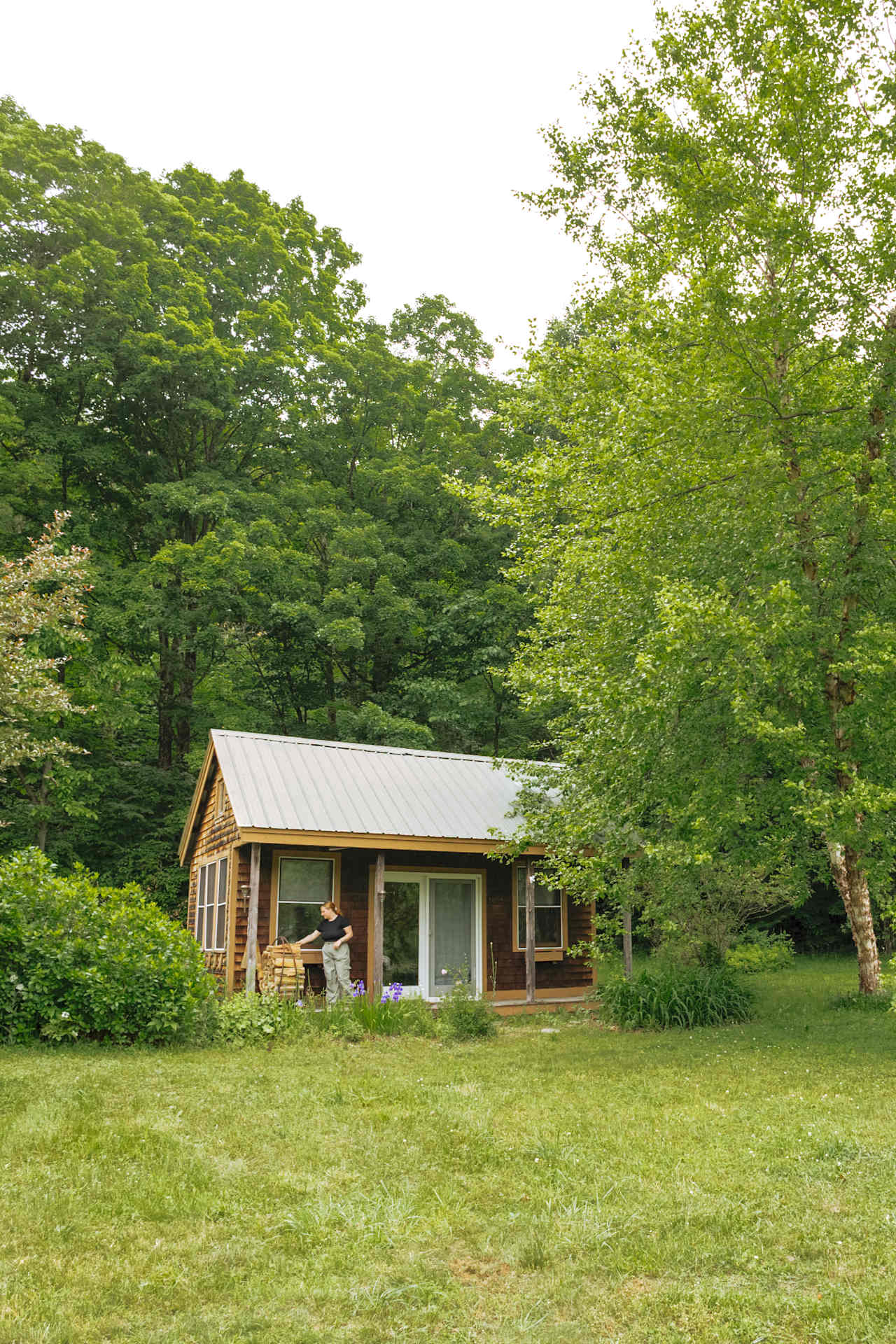 The cabin sits at the top of the meadow tucked against the trees. 