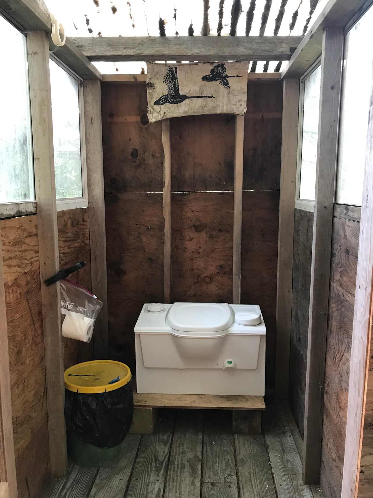 The outhouse with toliet. Feel free to “water the flowers” in the woods if you like. 