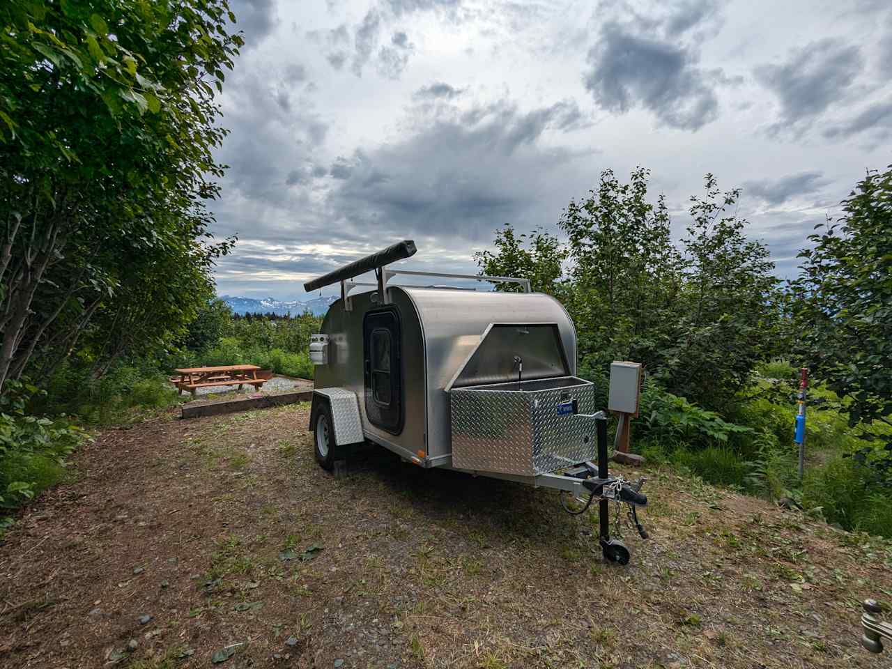 Electrical and well water hookups by the pad and picnic table with fire ring on river rocks to the back.