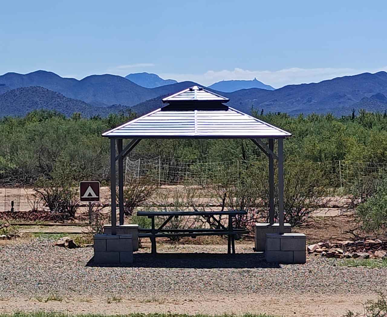 NEW for 2025!  Campsite Kitt is a spacious pull-through site with a hard covered 12x10 covered pavilion, picnic table, fire pit, trash can and a 12x12 tent pad.   The site can accommodate an RV or a tent.  This site gets it's name from Kitt Peak observatory  which can be seen in the far background of this photo.