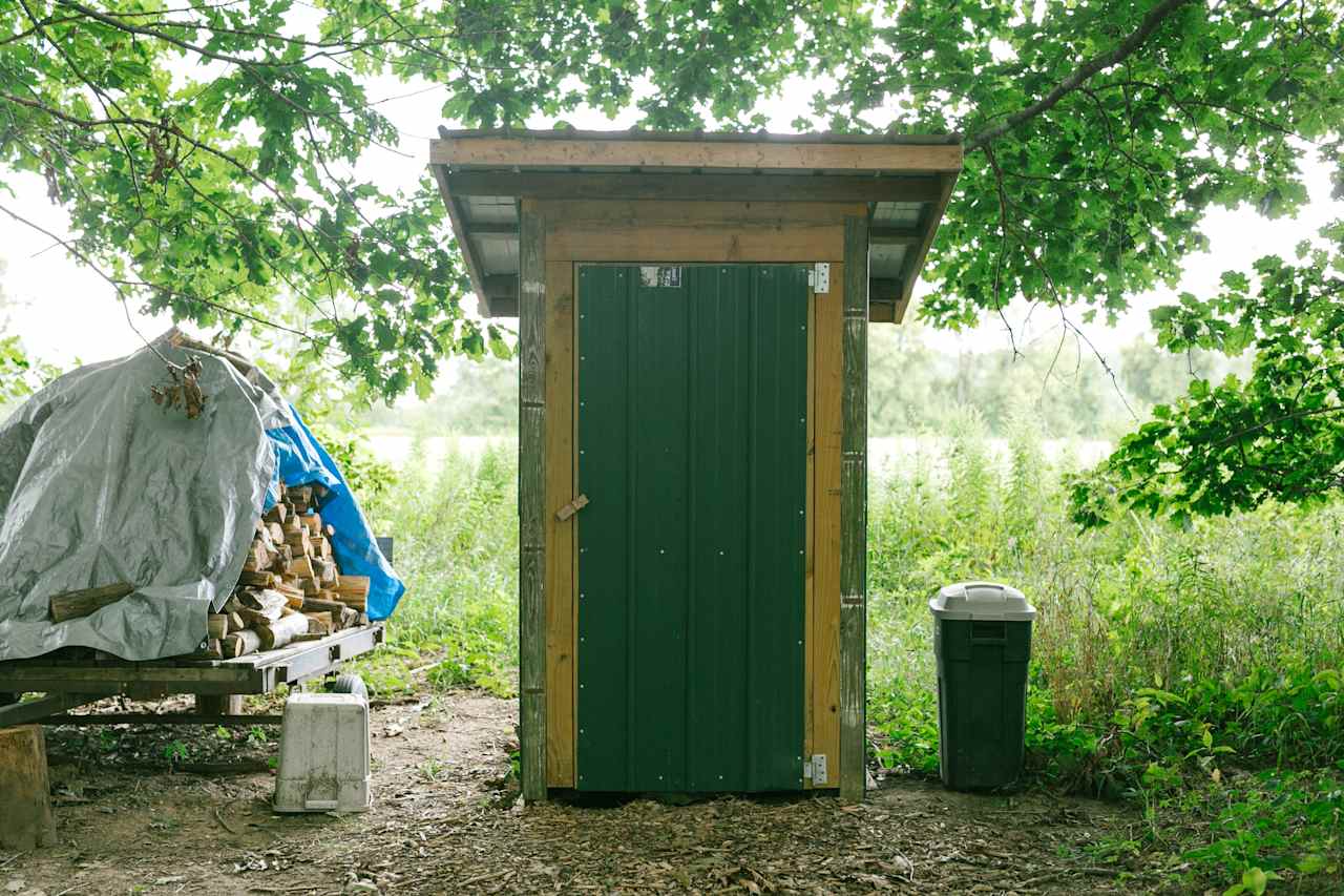 The firewood and the outhouse, located near the center of the camping area.