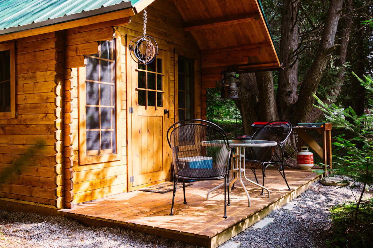 Small patio just outside the cabin, with a BBQ, table and chairs