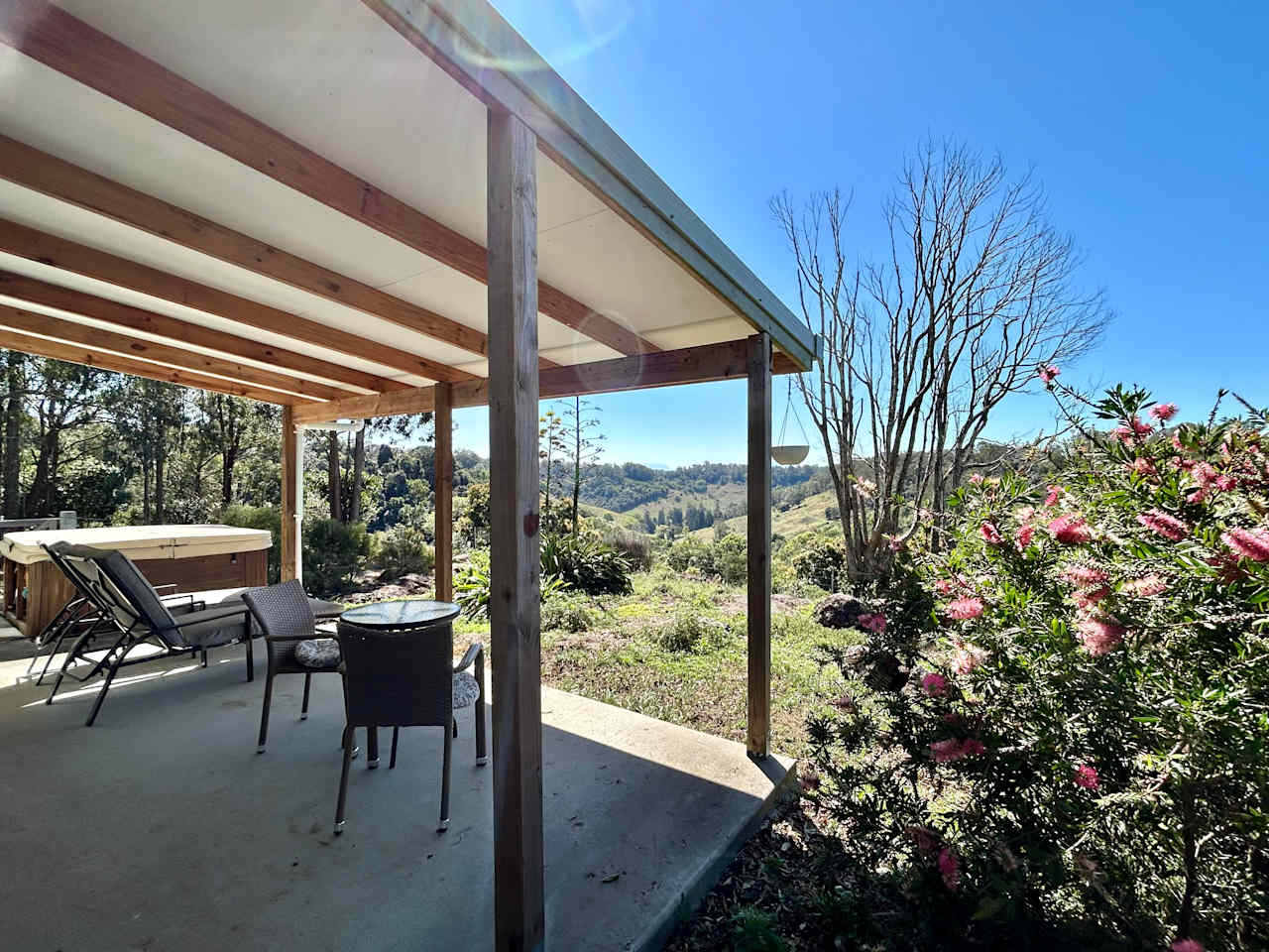 Furnished patio between the spa and bottlebrush trees, with views to the Border Ranges National Park.