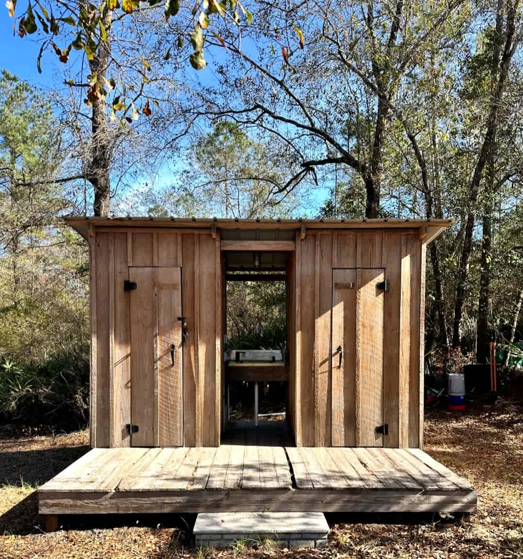 Outhouse-style bathroom with hand wash sink and electric 