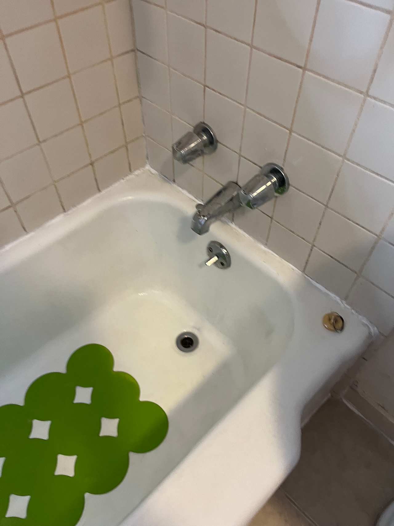 Bathtub surrounded by tiles which have been scrubbed with an electric brush, and Bathtub with fresh sealant. 