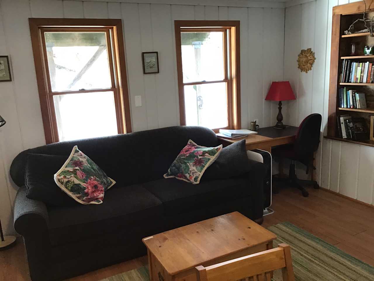 Sitting area facing kitchenette, sofa, coffee table, desk with office chair, book shelf 
