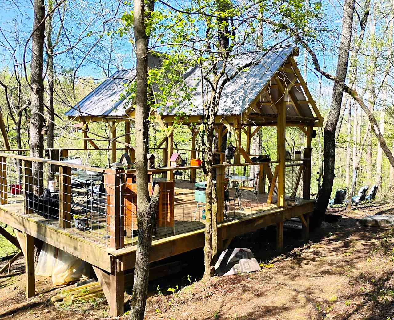 View of the Bird's Nest from the pathway, walking in. There is plenty of room for your family and group, for tents and hammocks. There is a campfire ring, more chairs, and hammocks to the right. And more chairs down below.