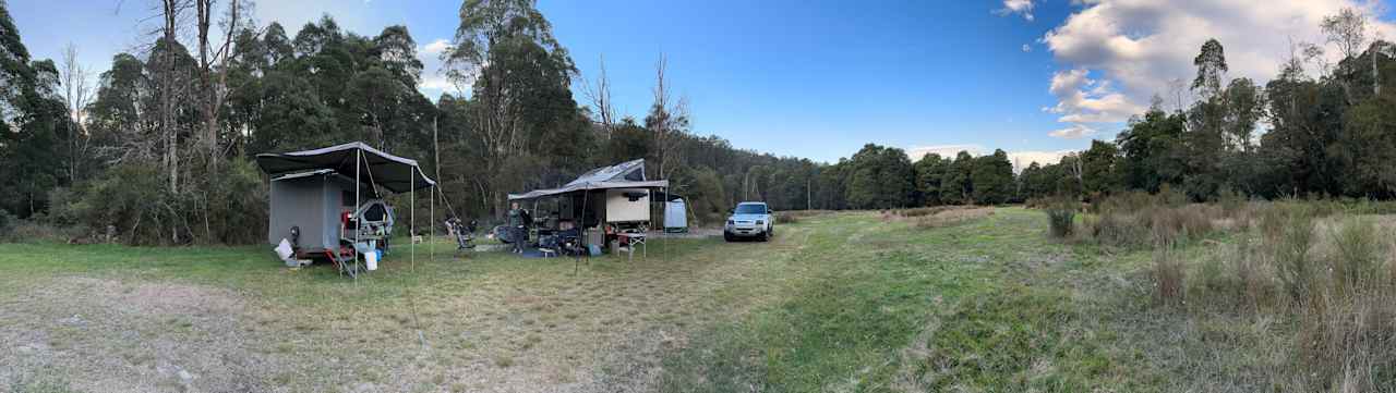 Site with river and trees on one side and grassy plain on other. 