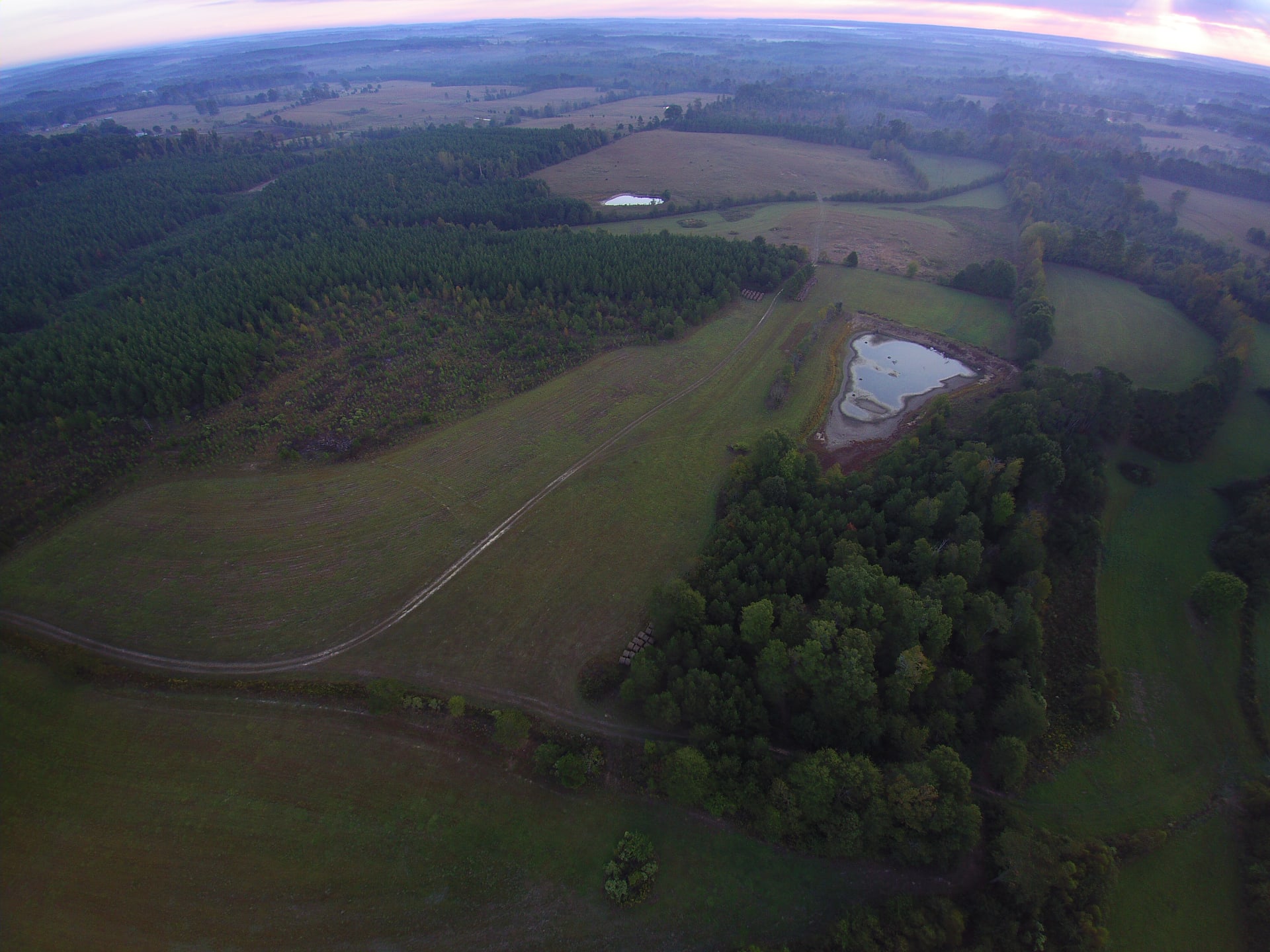 Drone shot from above house showing pond and pasture