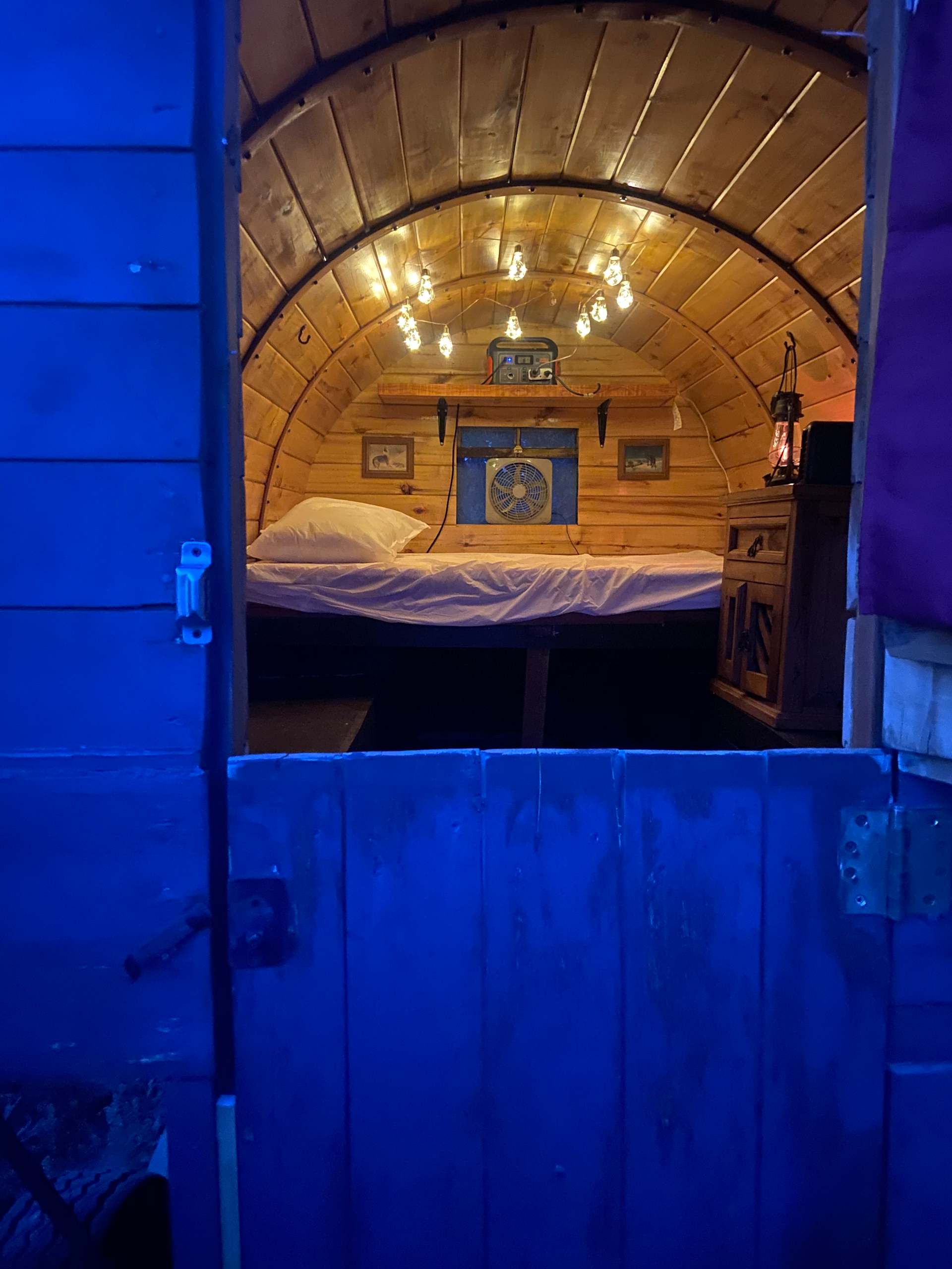 Inside of sheep herder cabin with mattress folded out and table pulls out underneath