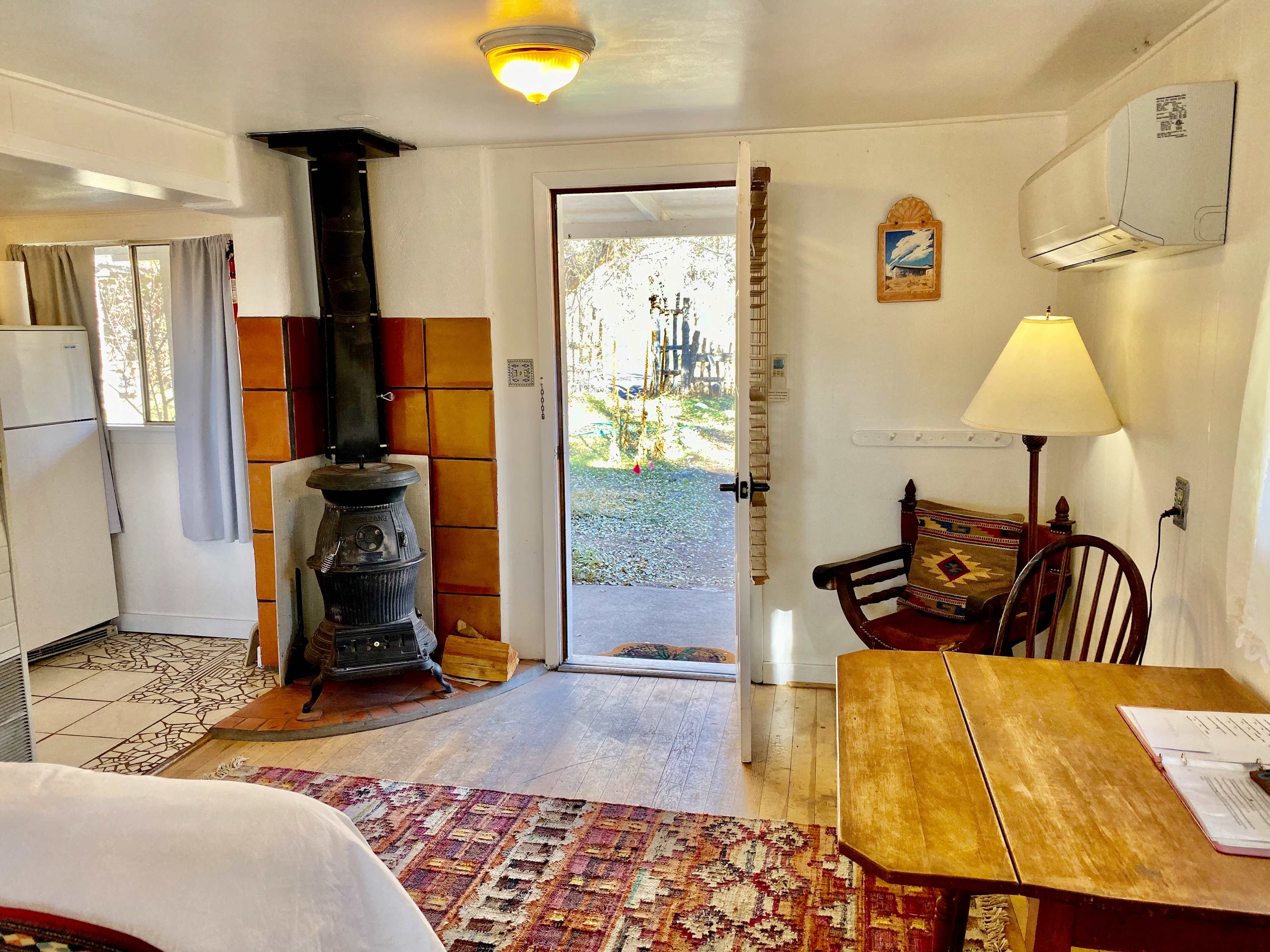 There is a wood fire stove. Outside is a porch with chairs and a table. 