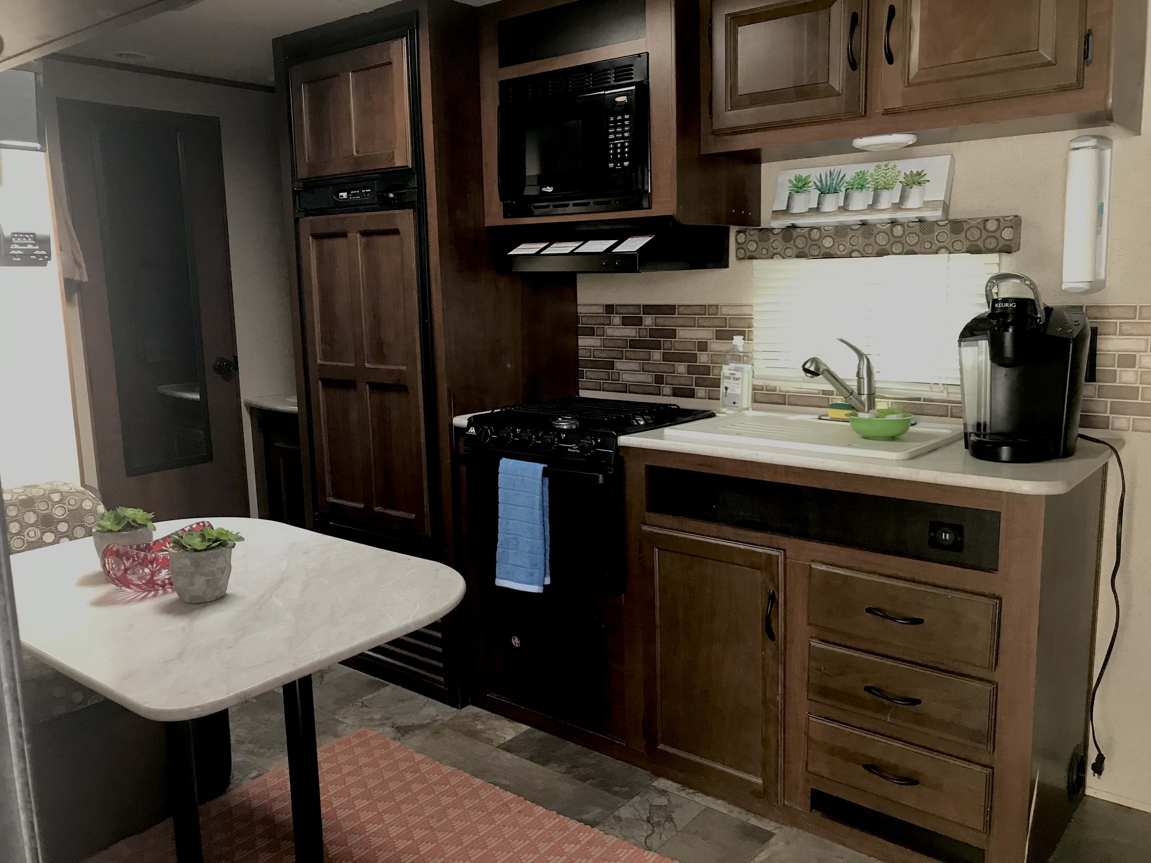 Kitchenette space with Fridge/ freezer, microwave, stove and small trailer over. 