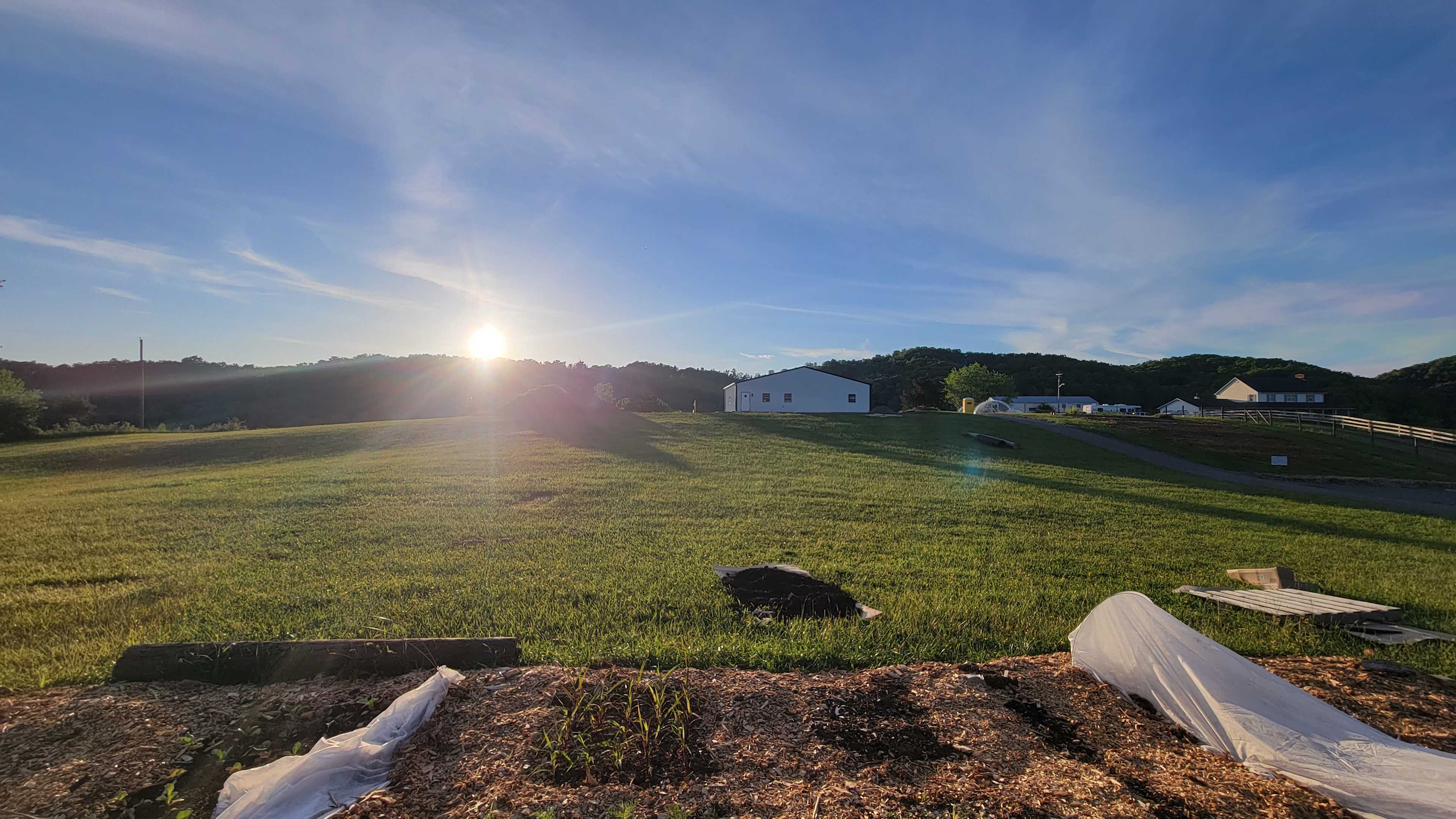 View from the road and pick-your-own garden. RV & Trailer parking between field in foreground and white Farm building.