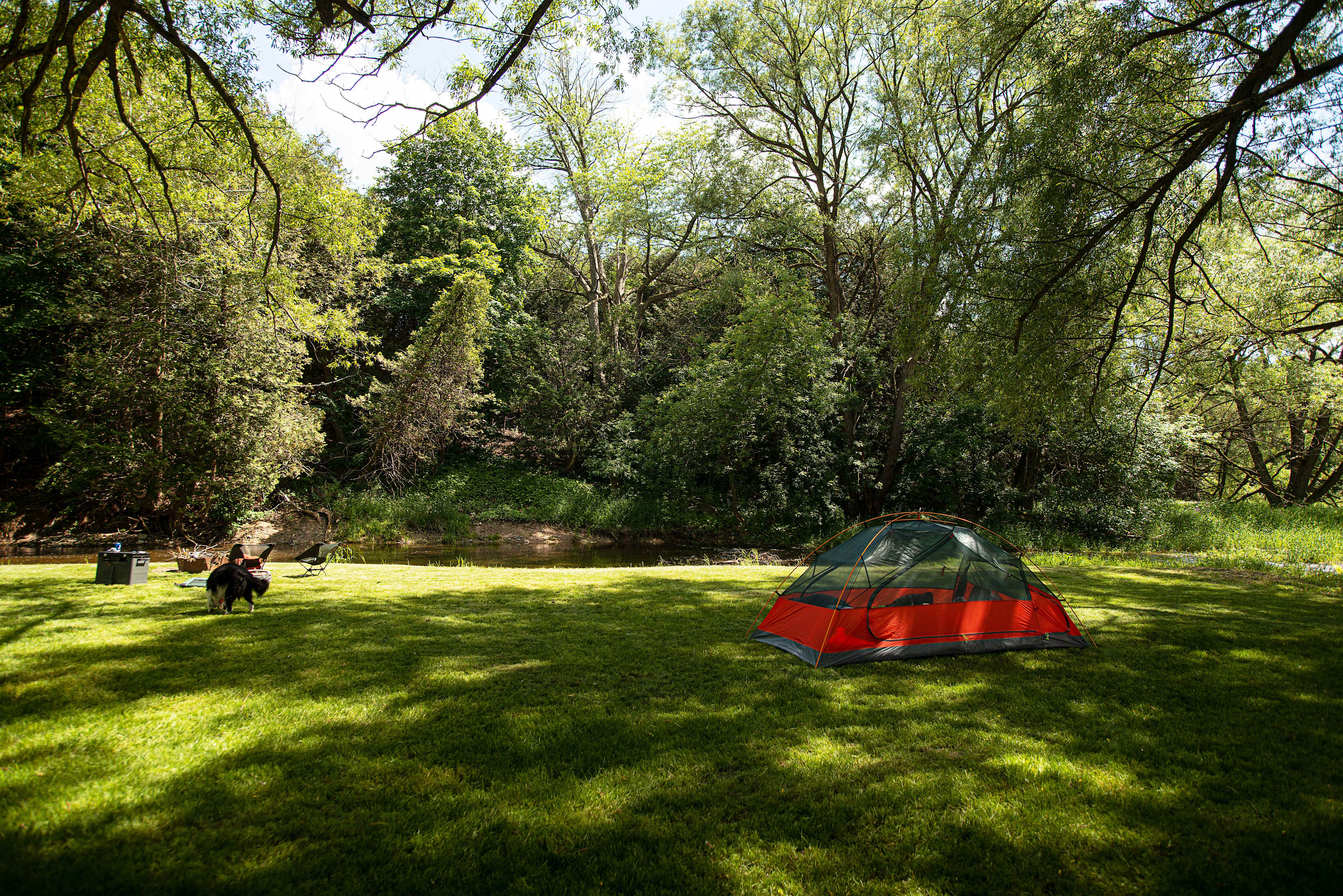 Overlooking site, tent, river, and fire pit.