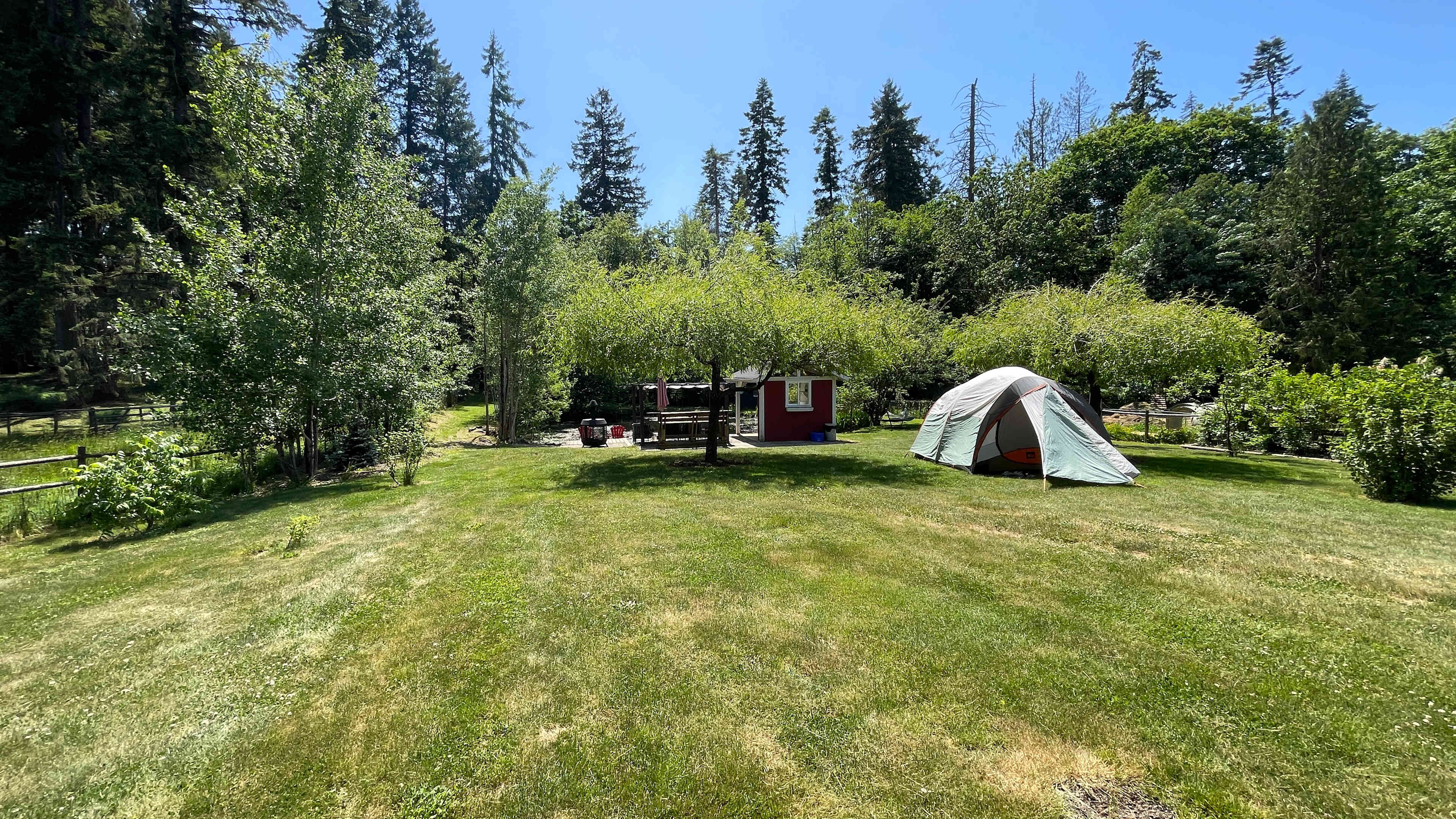 View from site#4 looking left to right at site#2 (empty) and site#1 (with tent). The background is the kitchenette, fire pit, and pond area.