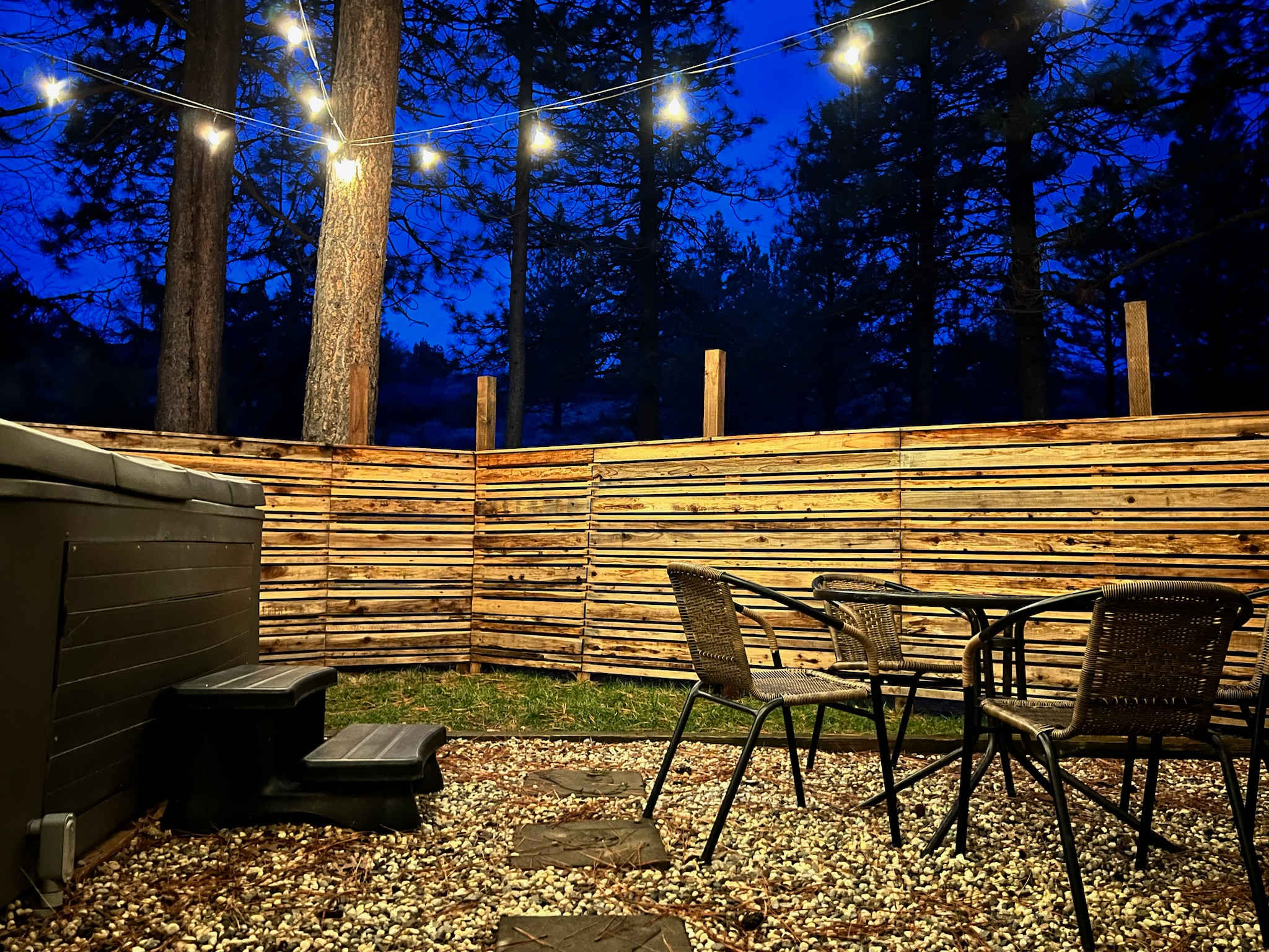 Private fenced back patio area with BBQ, patio table and chairs, and hot tub.