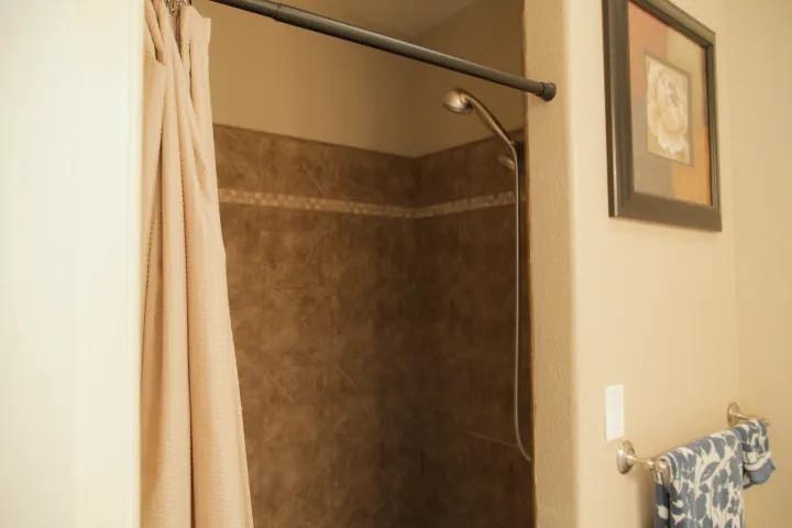 Large shower, with two shower heads and bench to sit on. 