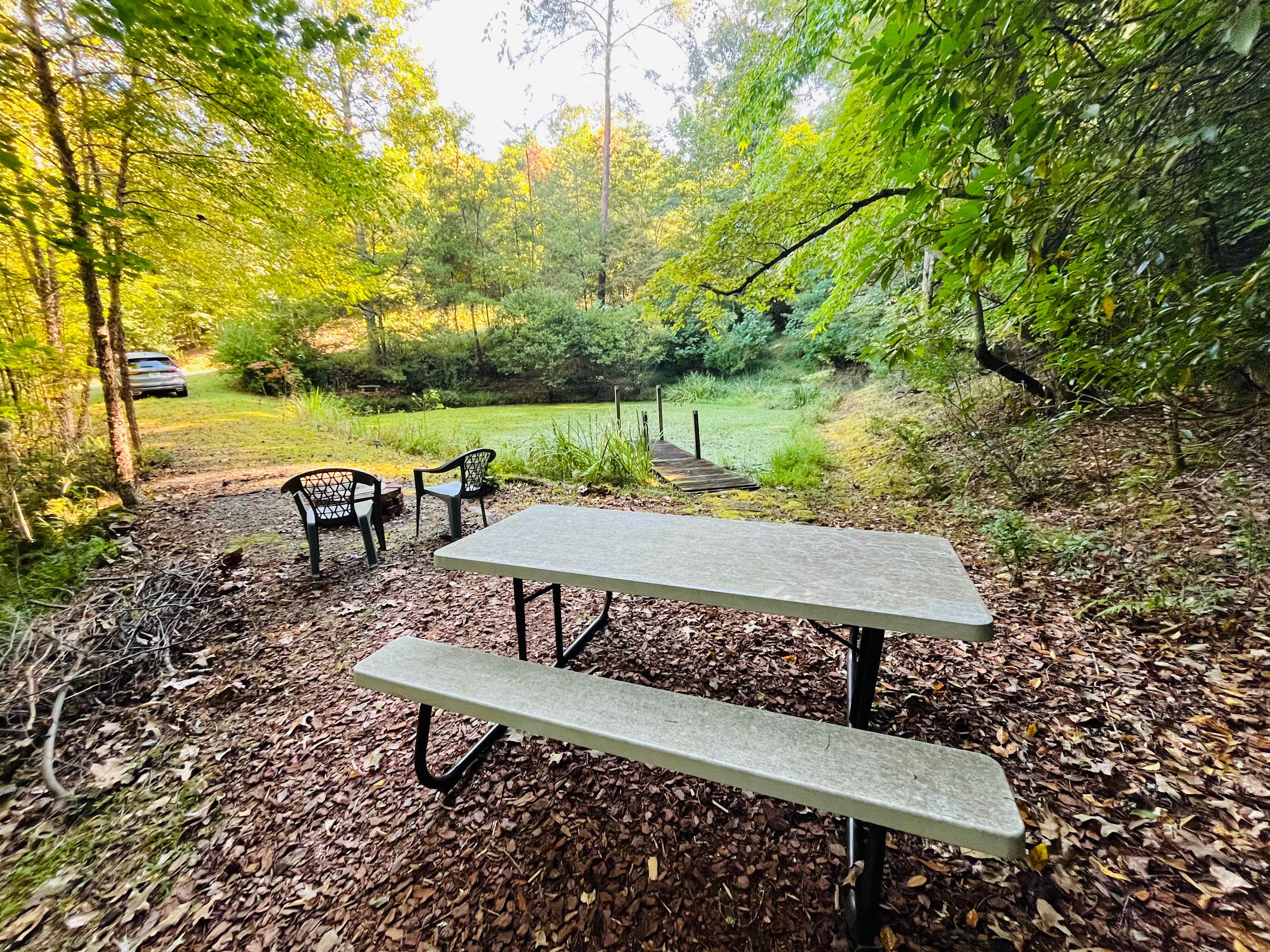 The picnic table is super lightweight and can be moved based on how you camp. It is on the flattest spot so if you sleep in a tent you can move the table to the other side of the fire pit and pitch your tent where the table is.