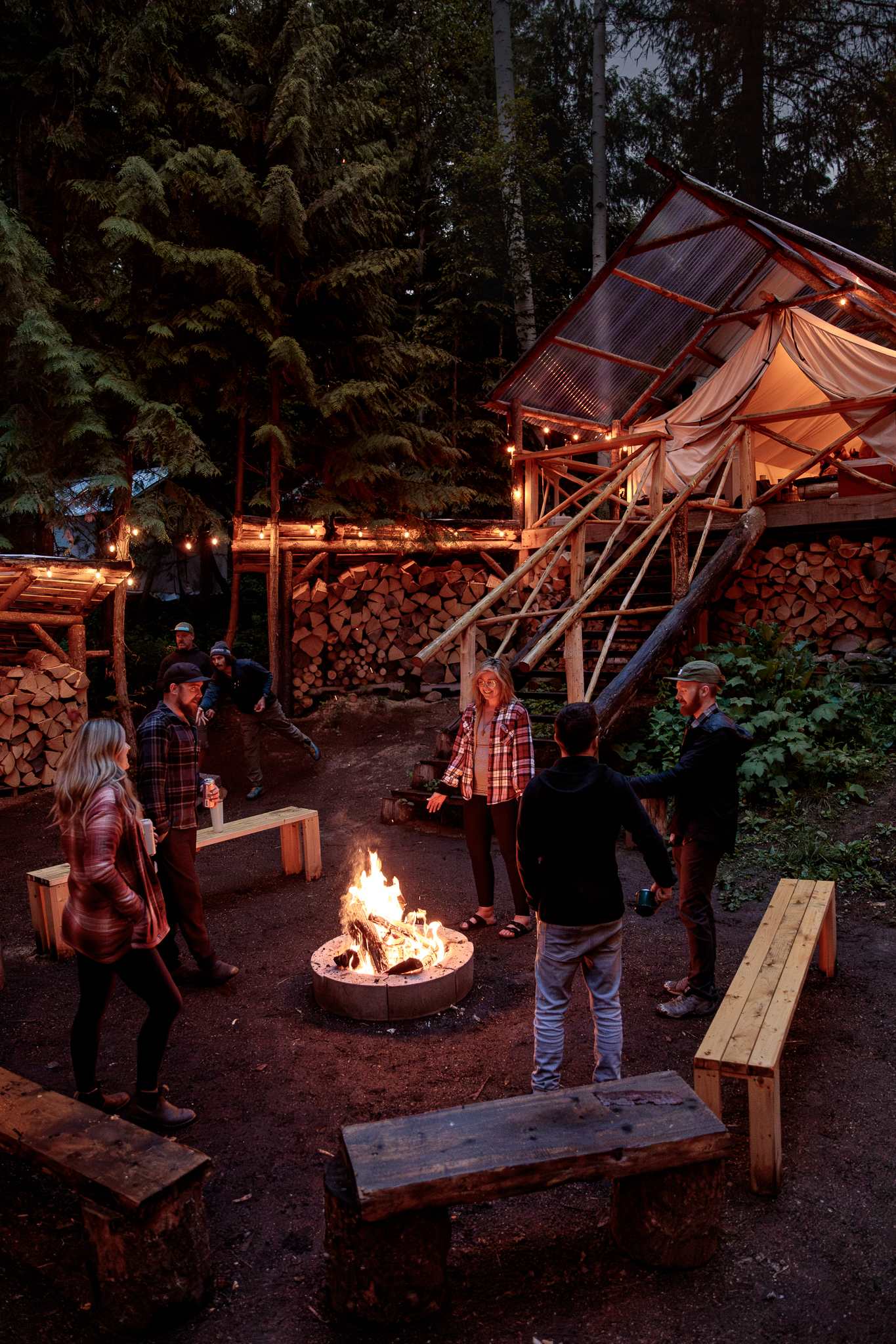 Guests enjoying the heart of the camp - the communal fire pit, cornhole, kitchen tent and outdoor kitchen. Use of all cooking supplies is included!