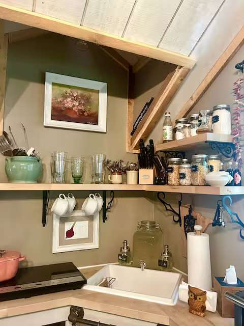 Kitchenette with two bar stools, Breville oven, cookstove, staples, herbs and spices, cookware, glasses, utensils, and recipe books. 