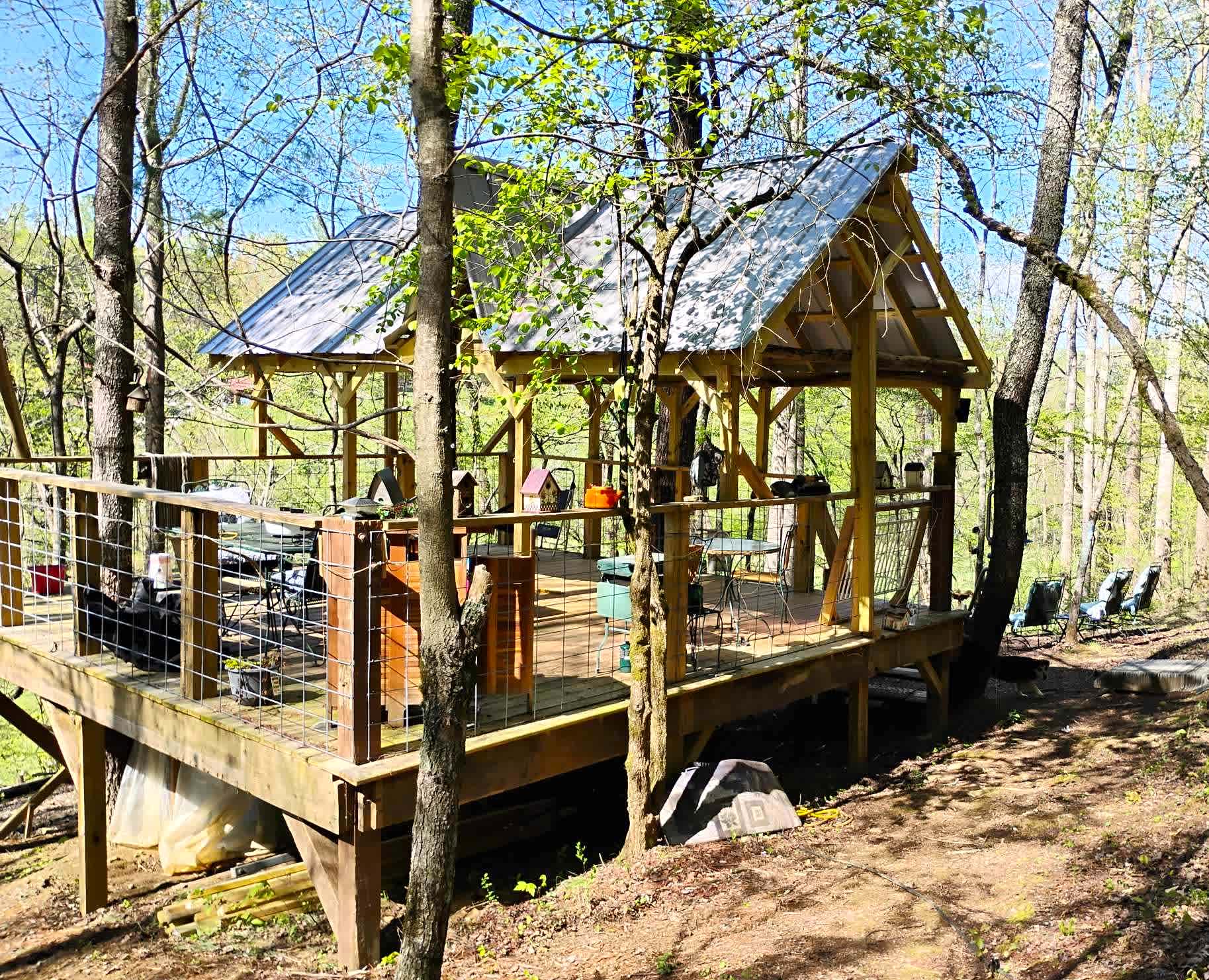 View of the Bird's Nest from the pathway, walking in. There is plenty of room for your family and group, for tents and hammocks. There is a campfire ring, more chairs, and hammocks to the right. And more chairs down below.