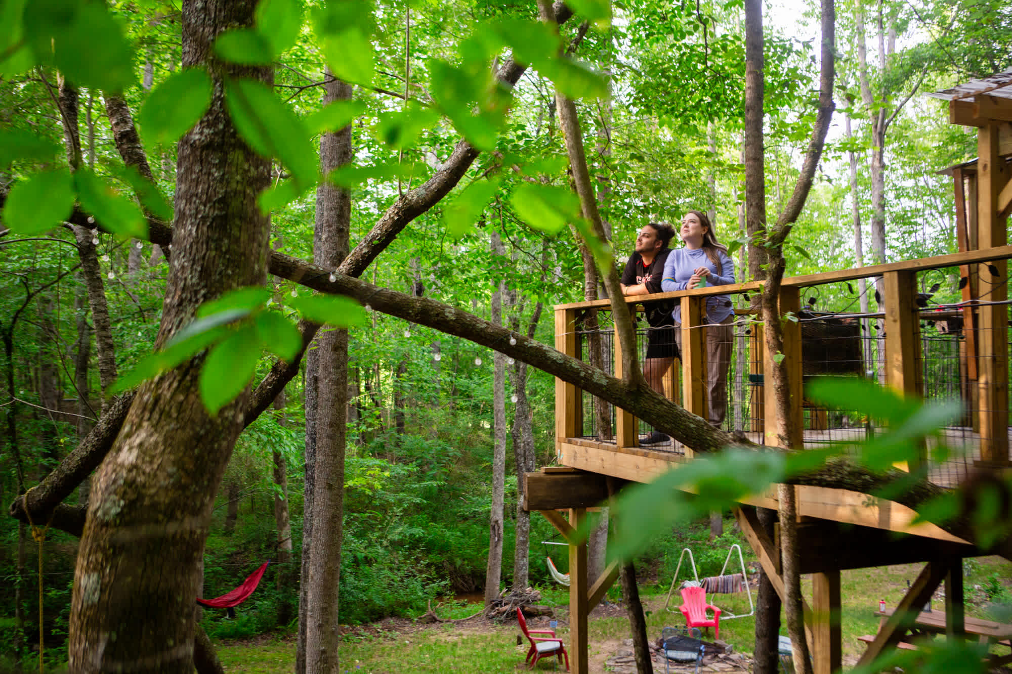 The treehouse's spacious porch balcony! You can also see the fire pit below with an abundance of chairs and hammocks placed thoughtfully all along the creek 