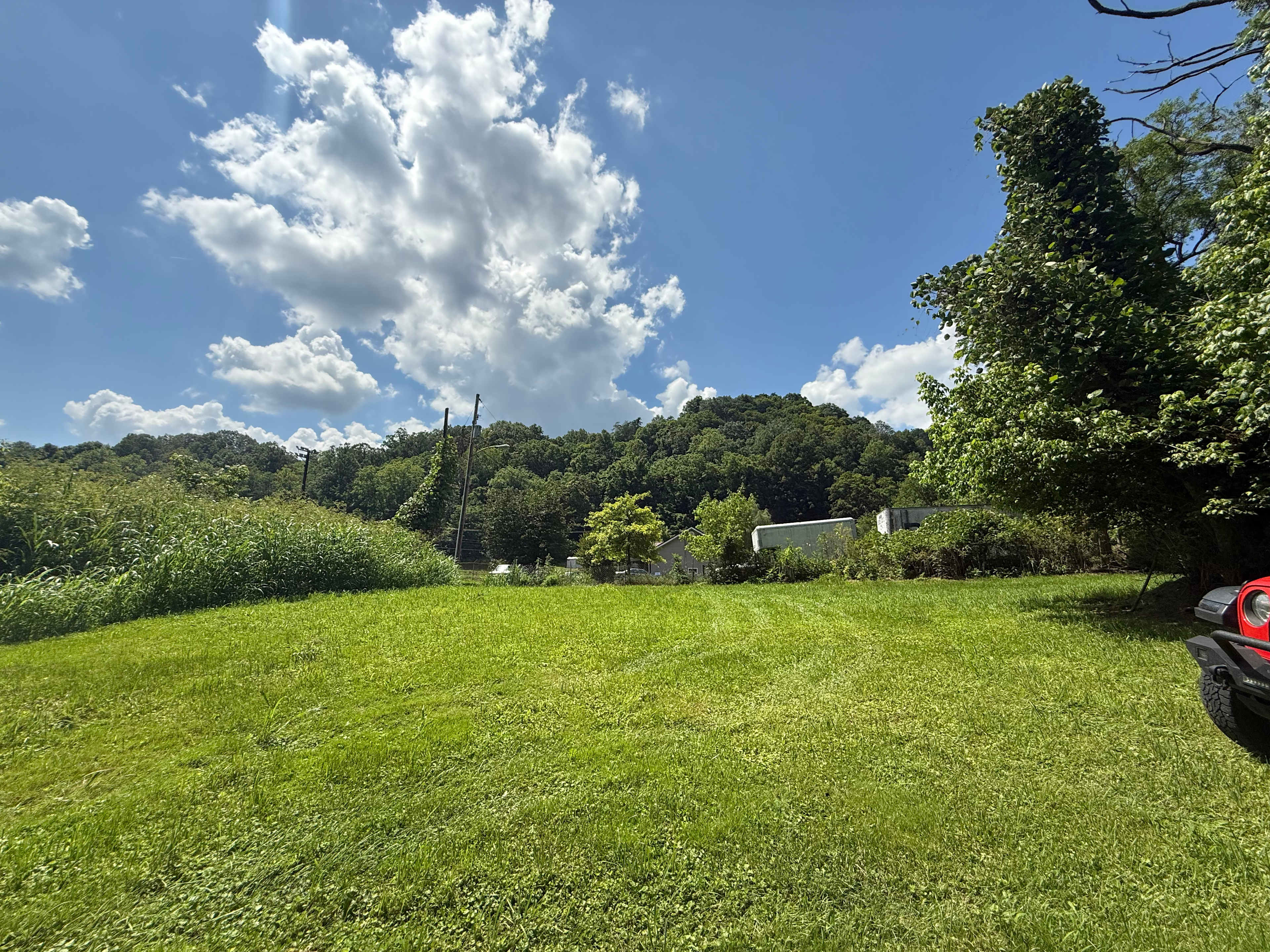 View from river looking to back of property to show neighboring property. There is a small natural barrier as well as storage shed/outbuildings between properties.