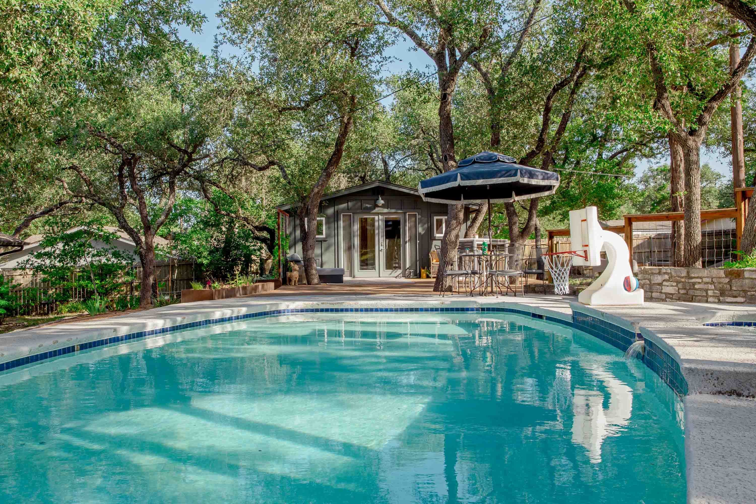 Enjoy a refreshing swim in the private pool with a view of the cozy guesthouse just steps away, an ideal setup for relaxing under the Texas sun.