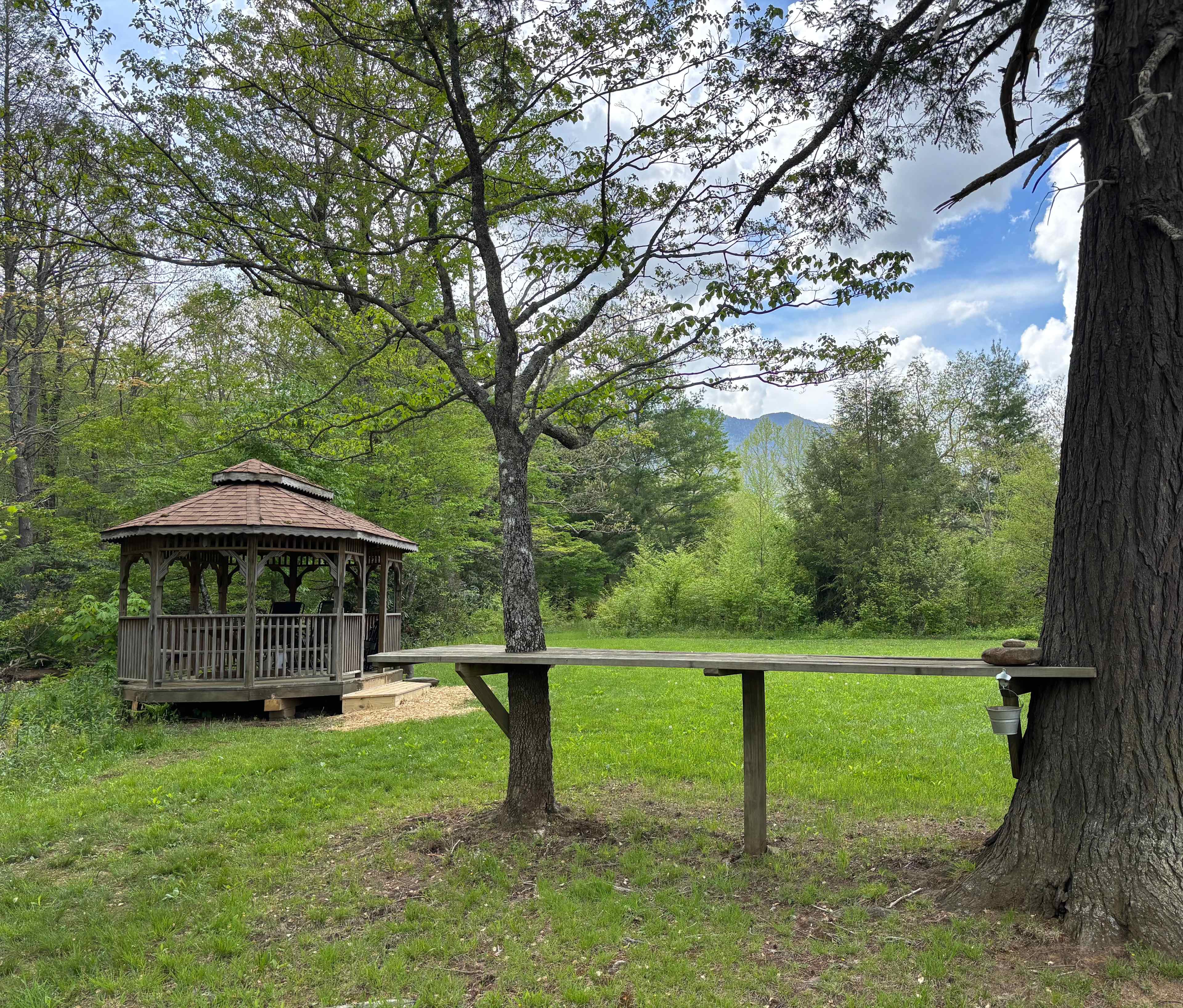 Gazebo, serving table, camping area and mountains in the background.