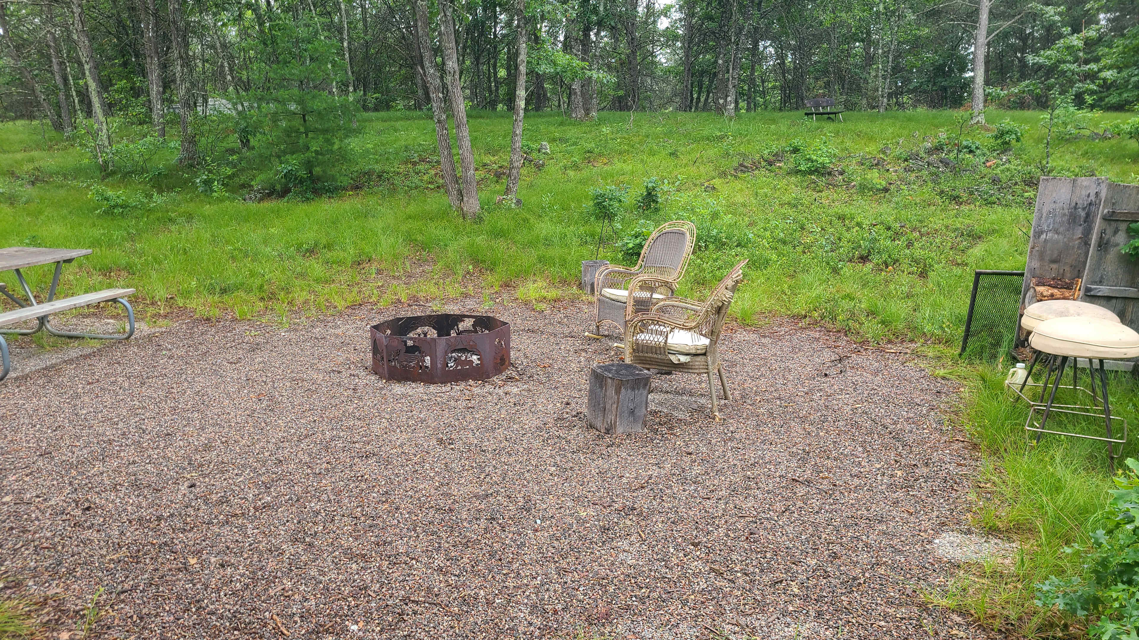Large fire pit, chairs/stools with cushions (wet), log pile, grate, expandable hot fog roasting stick, picnic table