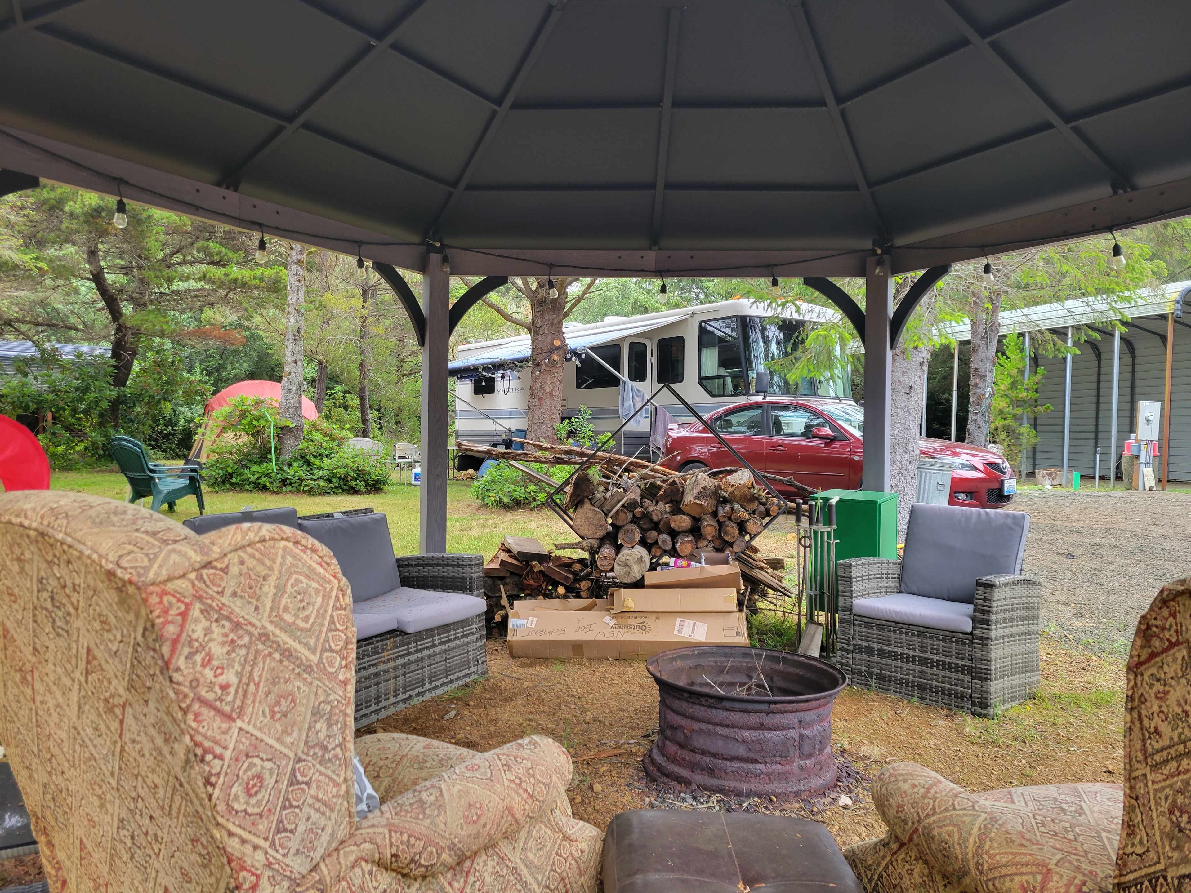 View of Uncovered Campsite (RV with hookups and space for large tent. Site #2 (Covered site) is in background). Picture taken from inside communal gazebo/firepit
