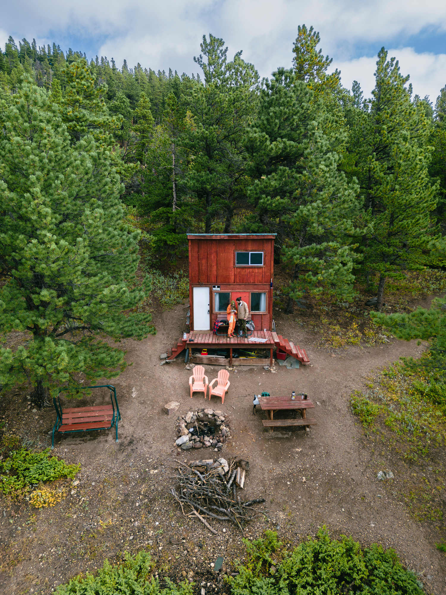 View of the cabin, fire pit. swing and chairs