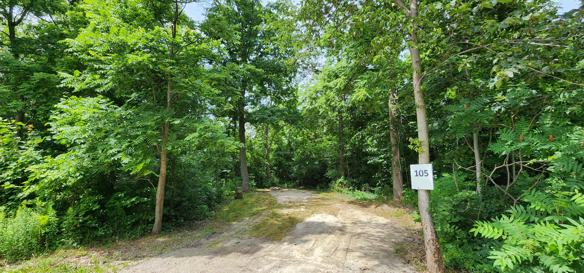 Site 105 entrance looking west. Small creek is directly to the right(north) and Site 106 directly to the left(south).
This is our longest site on the West side and fire pit is at the rear. Grade is about 2 degrees down to the northeast.